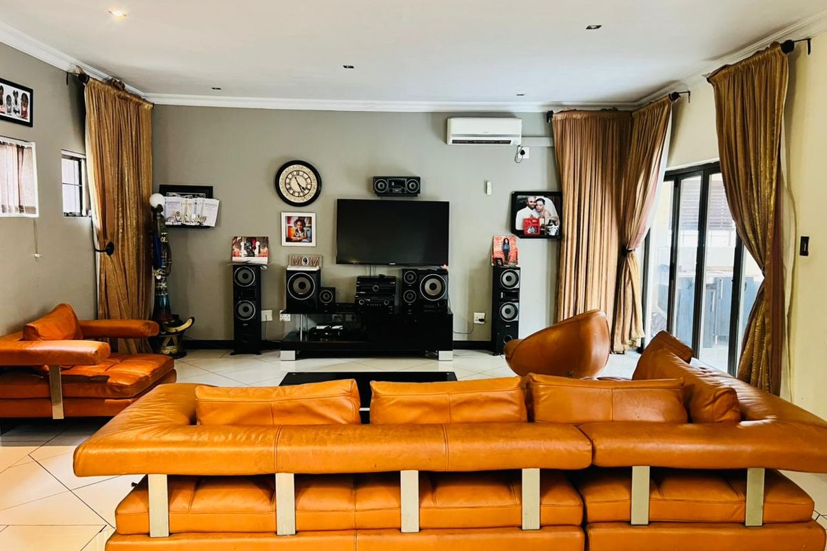 Spacious living room featuring tiled flooring, recessed lighting, and a wall-mounted air conditioning unit, with direct access to an outdoor area via sliding glass doors.