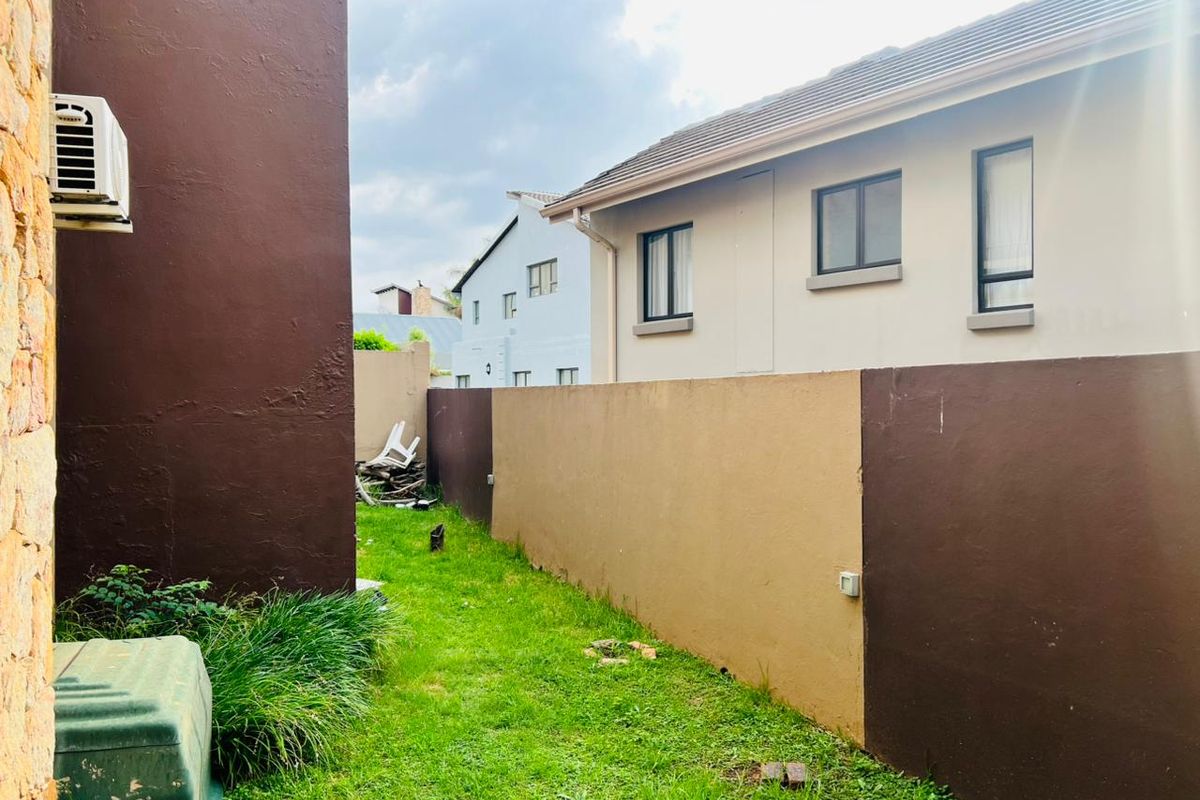 A side garden area featuring a lawn, boundary walls, and an exterior air conditioning unit attached to the building structure.