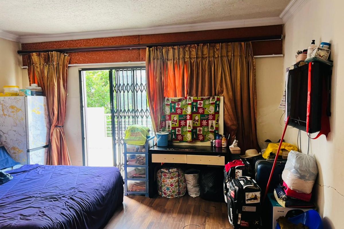 A bedroom featuring laminate flooring, crown molding, and a sliding glass door with a security gate leading to an outdoor area.