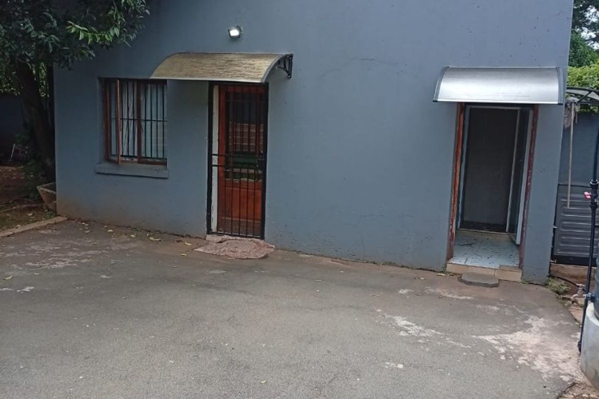 Rear exterior view of the property featuring a grey rendered facade, security gates, and protective awnings over the entrances.