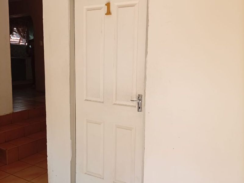 A simple interior hallway featuring tiled flooring and a numbered internal door leading to a room.