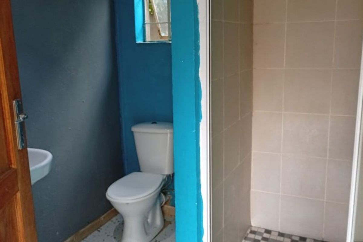 A functional bathroom featuring a shower enclosure, toilet, and wall-mounted basin, requiring cosmetic updates to finishes and paintwork.