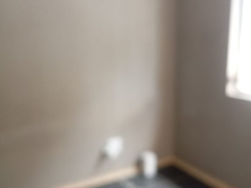 A vacant room featuring tiled flooring and neutral wall finishes, currently presented in a blurry photograph.