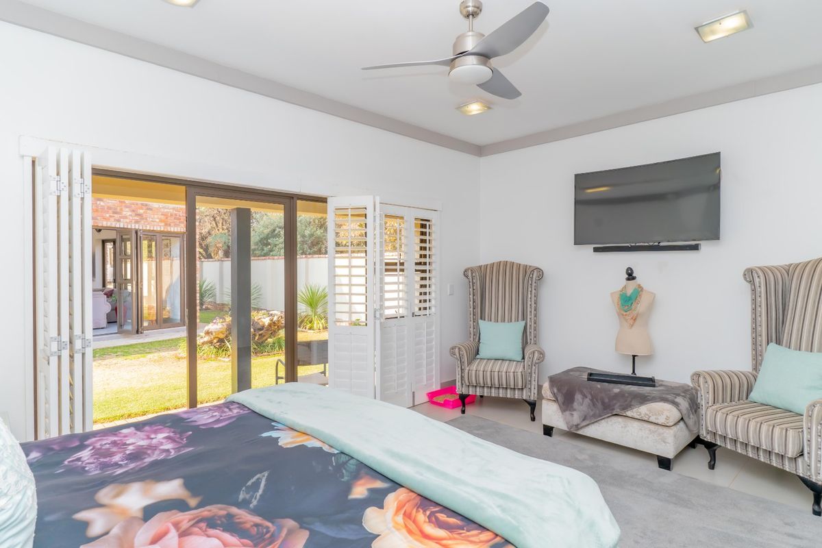 Spacious bedroom featuring a ceiling fan, recessed lighting, and large sliding glass doors with plantation shutters providing direct access to the garden.