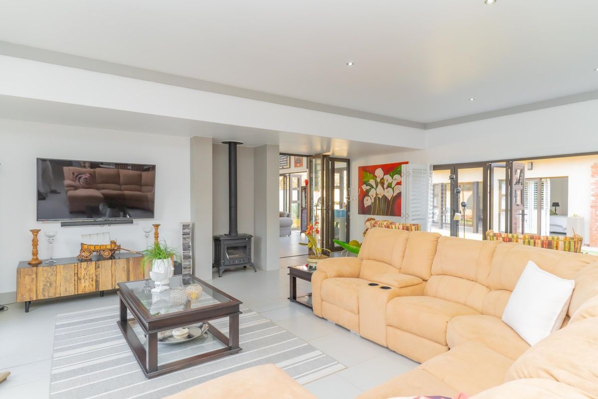 Spacious living room featuring a freestanding wood-burning fireplace, neutral tiled flooring, and large bi-fold doors providing seamless access to the outdoor area.