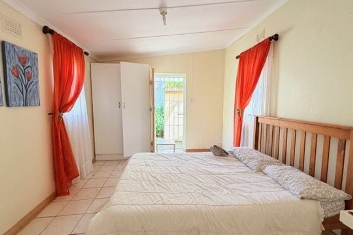 A bedroom featuring tiled flooring, a built-in wardrobe, and direct access to an exterior area through a security gate.