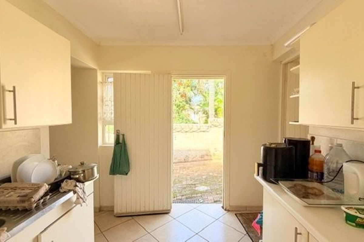 A functional kitchen featuring built-in cabinetry, tiled flooring, and direct access to the exterior through a rear door.