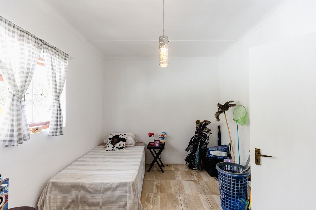 A compact bedroom featuring tiled flooring, a central pendant light fixture, and coved ceiling details.