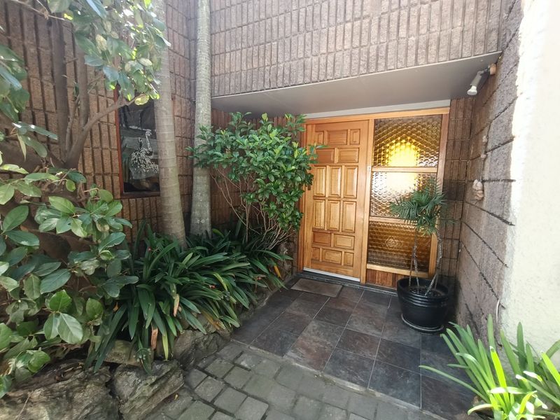A welcoming front entrance featuring a solid timber door, decorative textured glass sidelight, and durable slate floor tiles set against a brick facade.
