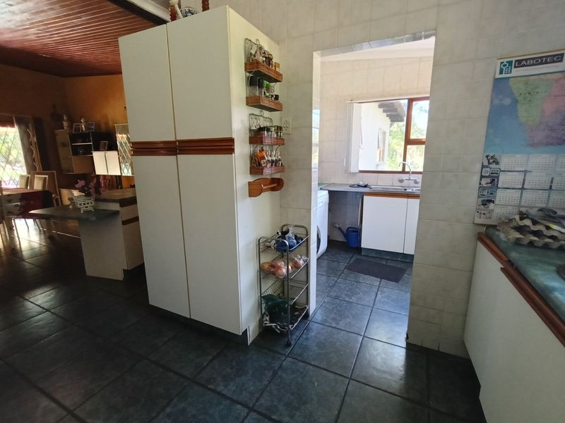 A functional scullery area featuring tiled flooring, built-in cabinetry, and a stainless steel sink, providing a practical secondary workspace adjacent to the main living area.