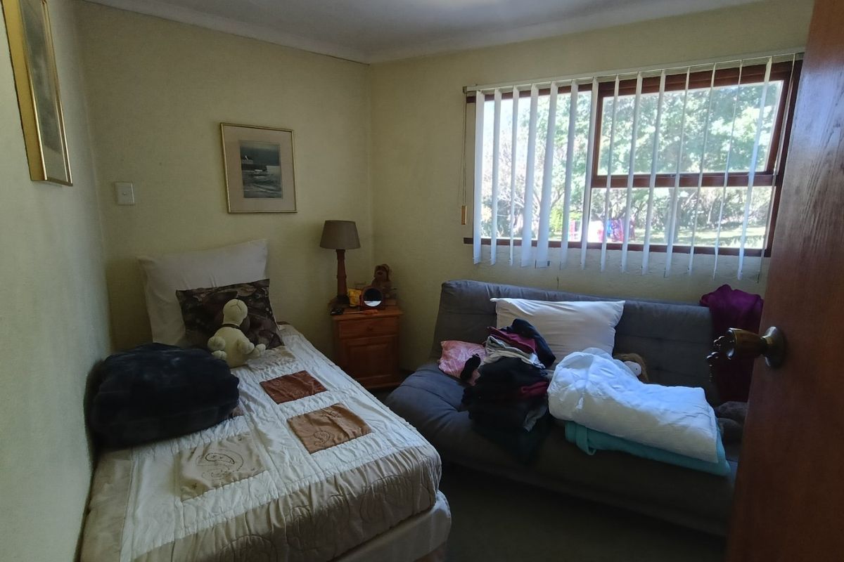A functional bedroom featuring carpeted flooring, neutral wall finishes, and vertical window blinds providing natural light.