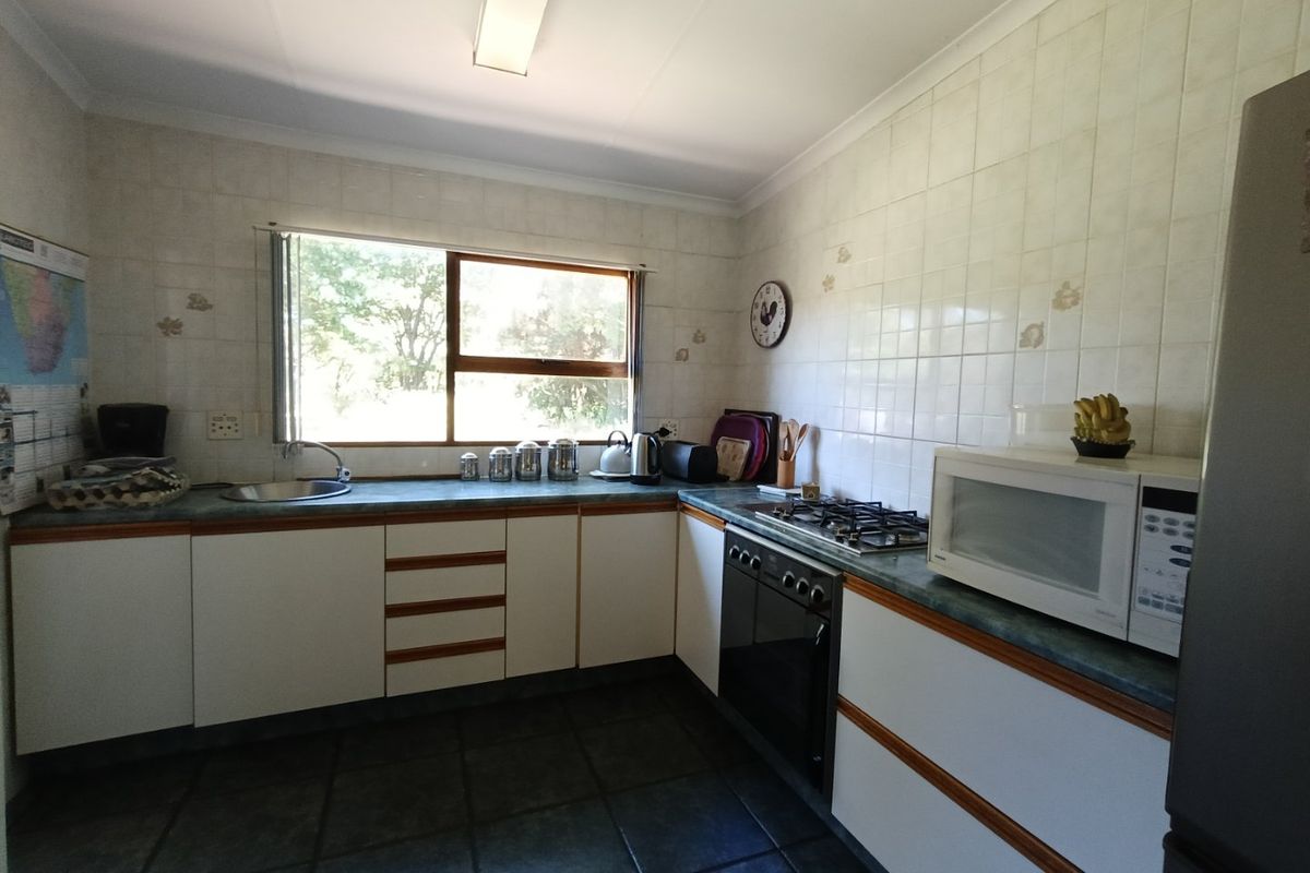 A functional kitchen featuring white cabinetry, laminate countertops, a gas hob, built-in oven, and tiled finishes throughout.
