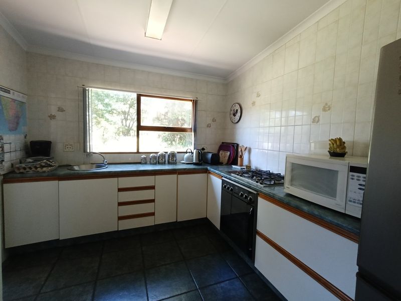 A functional kitchen featuring white cabinetry, laminate countertops, a gas hob, built-in oven, and tiled finishes throughout.