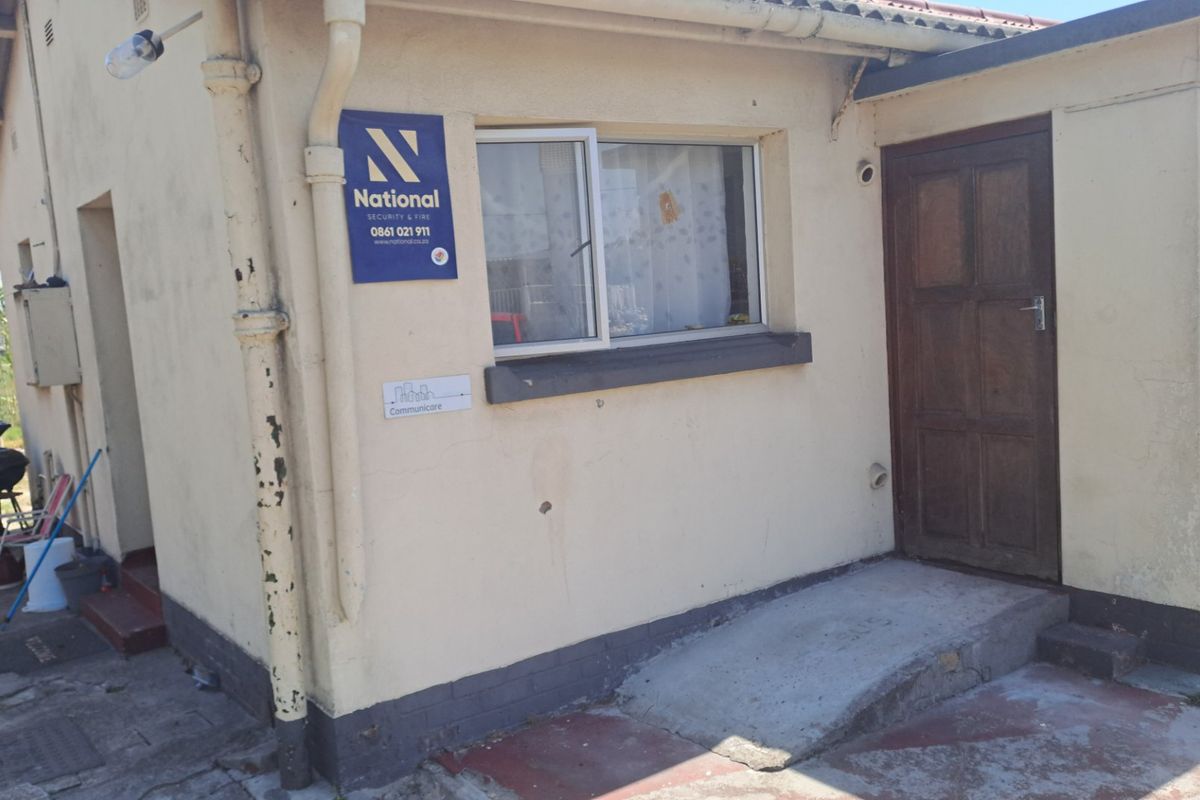 Front exterior view of the property featuring a timber entrance door, sliding window, and concrete access ramp with visible signs of wear and maintenance needs.