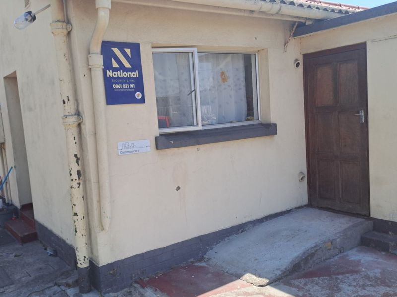 Front exterior view of the property featuring a timber entrance door, sliding window, and concrete access ramp with visible signs of wear and maintenance needs.