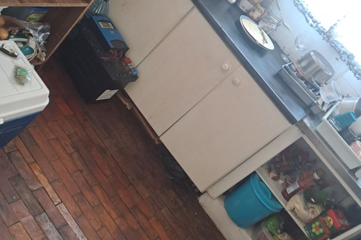 A compact kitchen area featuring timber parquet flooring and basic cabinetry, currently requiring maintenance and cosmetic updates to improve functionality and aesthetic appeal.