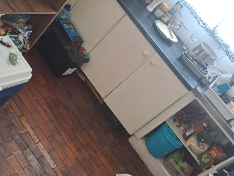 A compact kitchen area featuring timber parquet flooring and basic cabinetry, currently requiring maintenance and cosmetic updates to improve functionality and aesthetic appeal.