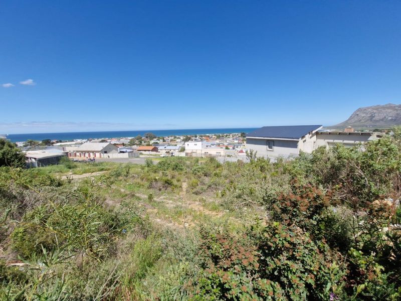 A scenic elevated view overlooking the coastal town, surrounding residential area, and distant mountains from the vacant residential land.