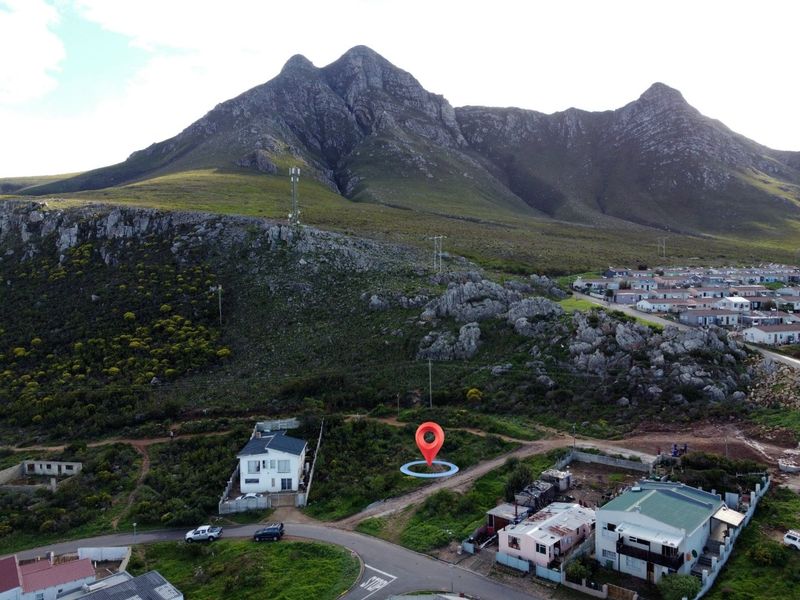 Aerial view of a vacant residential plot situated at the base of a mountain, offering scenic landscape views.