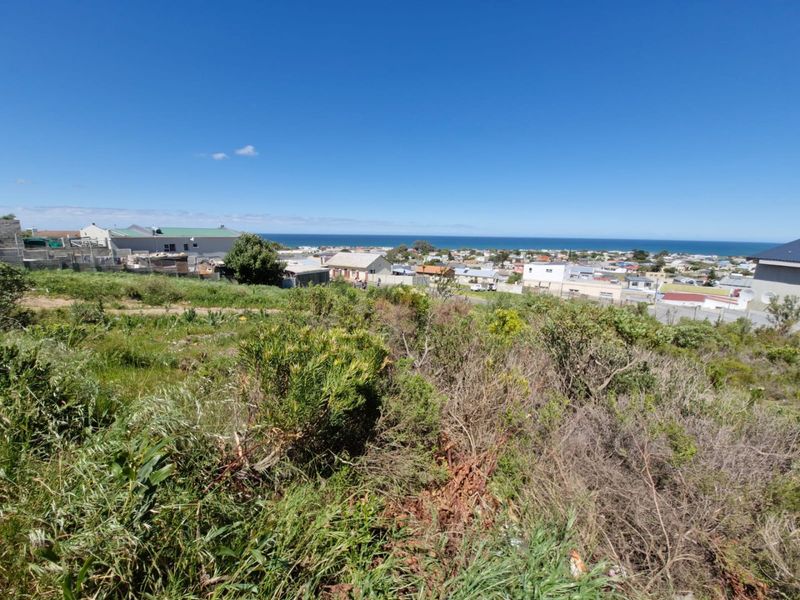 A scenic view overlooking the coastal residential area and the ocean from the elevated vacant land plot.