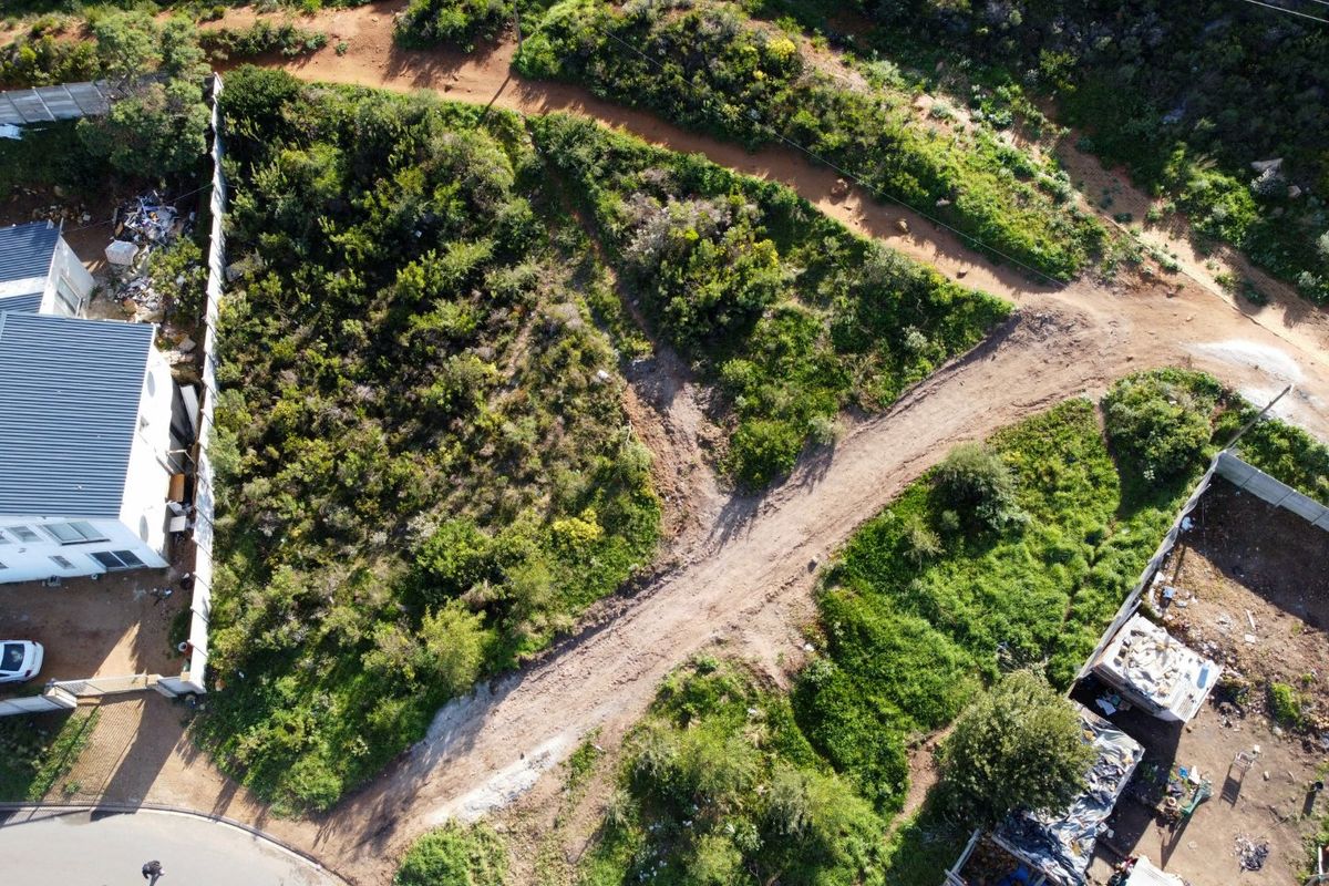 Aerial view of a vacant residential plot featuring natural vegetation, dirt access paths, and surrounding boundary fencing.