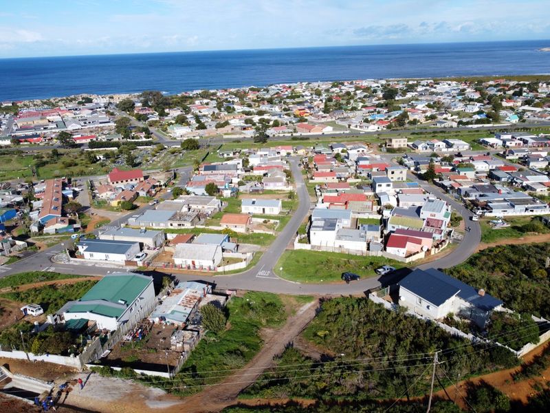 Aerial view of a coastal residential neighbourhood featuring established housing, road infrastructure, and available vacant land plots near the ocean.