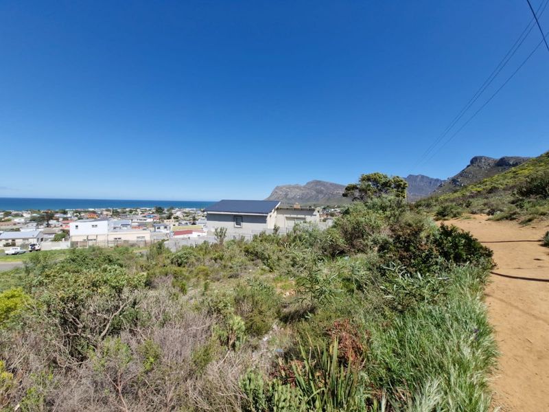 A scenic elevated view overlooking the coastal town, surrounding residential area, and distant mountain range.
