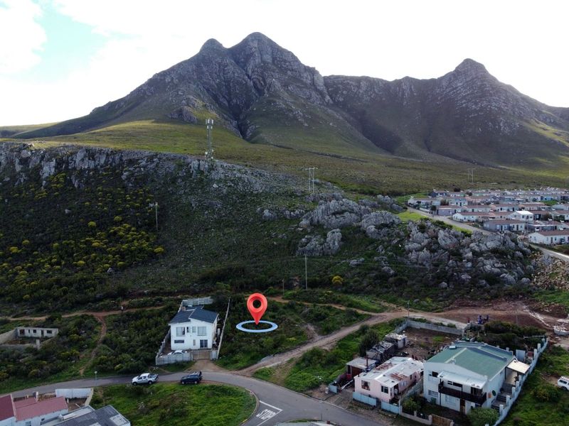 Aerial view of a vacant residential plot situated at the base of a mountain, offering scenic landscape potential.
