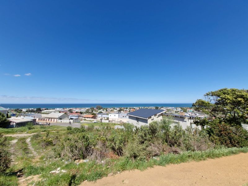 A wide-angle view overlooking the coastal town and ocean, showcasing the elevated position and scenic outlook of the vacant residential land.