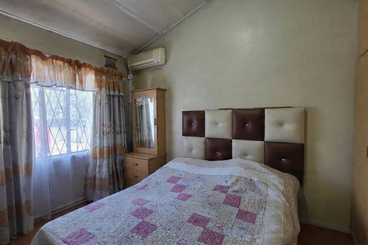 A bedroom featuring a built-in wardrobe, split-system air conditioning, and security bars on the window, requiring cosmetic updates to improve its overall condition.