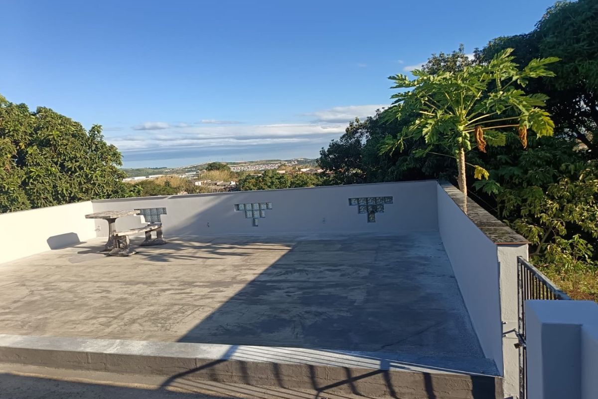 An open-air rooftop terrace featuring a concrete parapet wall with decorative glass block inserts and panoramic views of the surrounding area.