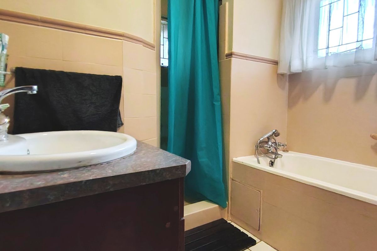 A functional bathroom featuring a vanity with basin, a bathtub with shower mixer, and tiled wall finishes.