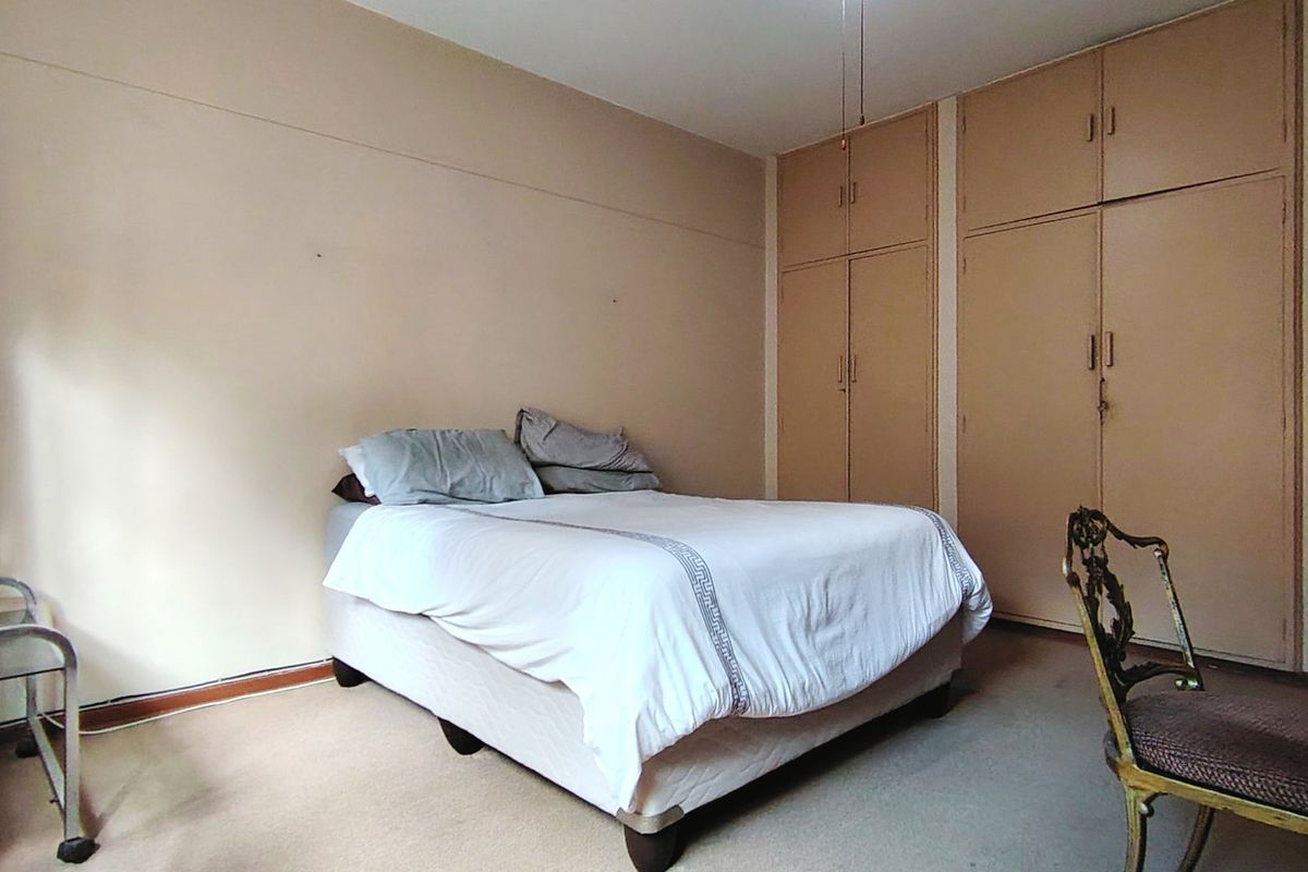 A bedroom featuring built-in cupboards and carpeted flooring, offering a functional space with potential for cosmetic updates to modernize the interior finishes.