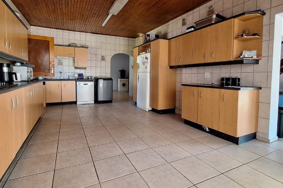 Spacious kitchen featuring extensive laminate cabinetry, tiled flooring, and a timber-clad ceiling, offering a functional layout with ample storage and workspace.