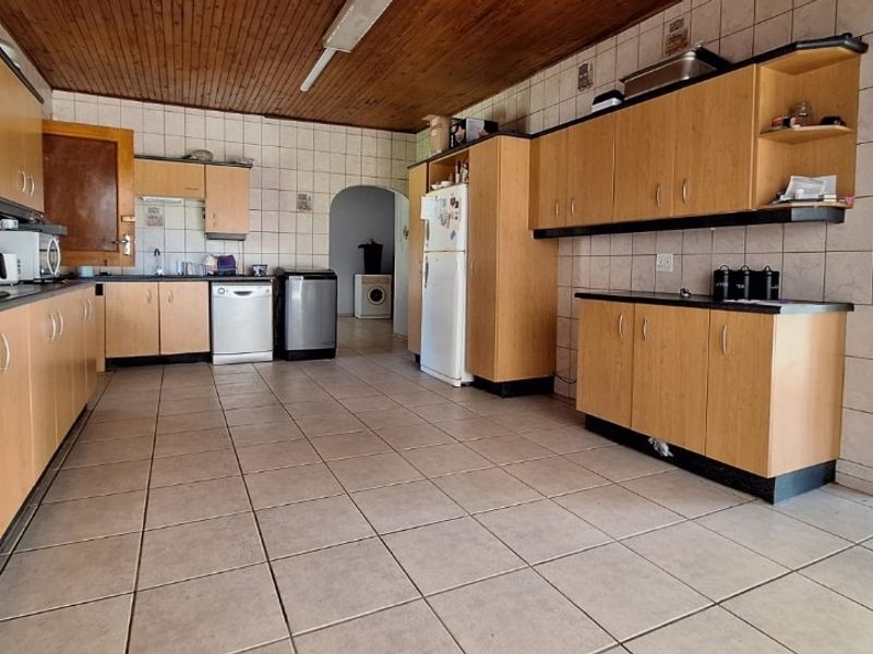 Spacious kitchen featuring extensive laminate cabinetry, tiled flooring, and a timber-clad ceiling, offering a functional layout with ample storage and workspace.