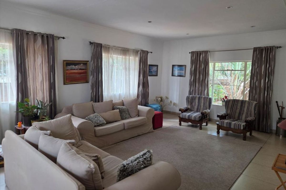 A spacious living room featuring tiled flooring, recessed ceiling lighting, and large windows that provide ample natural light.