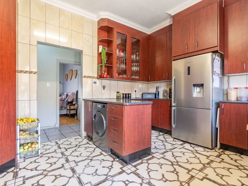 A functional kitchen featuring dark wood-look cabinetry, patterned tiled flooring, tiled backsplash, and integrated laundry appliance space.