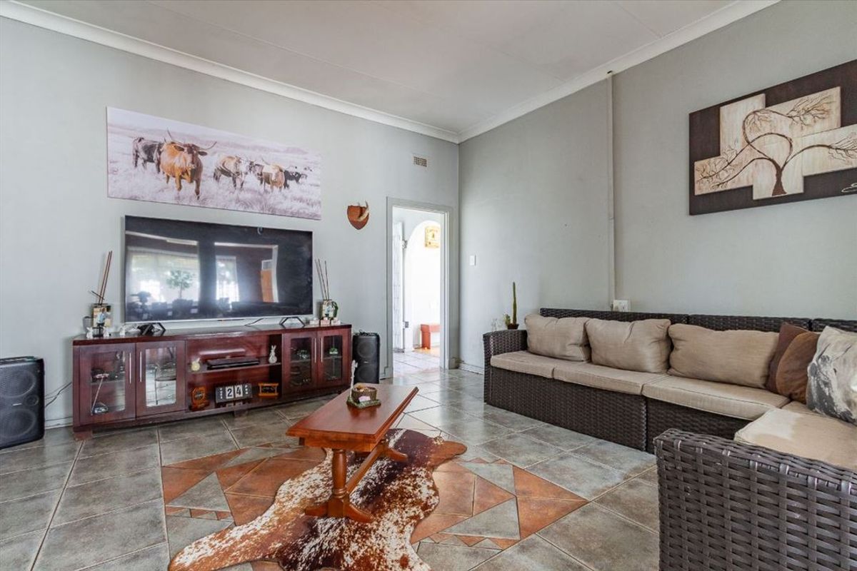 A spacious living room featuring tiled flooring with decorative inlay and coved ceilings, providing a functional and comfortable living space.