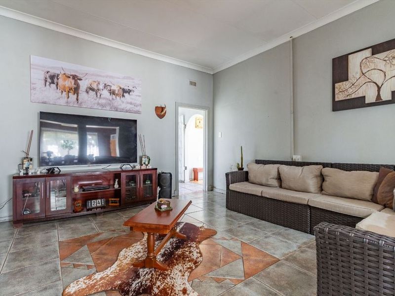 A spacious living room featuring tiled flooring with decorative inlay and coved ceilings, providing a functional and comfortable living space.