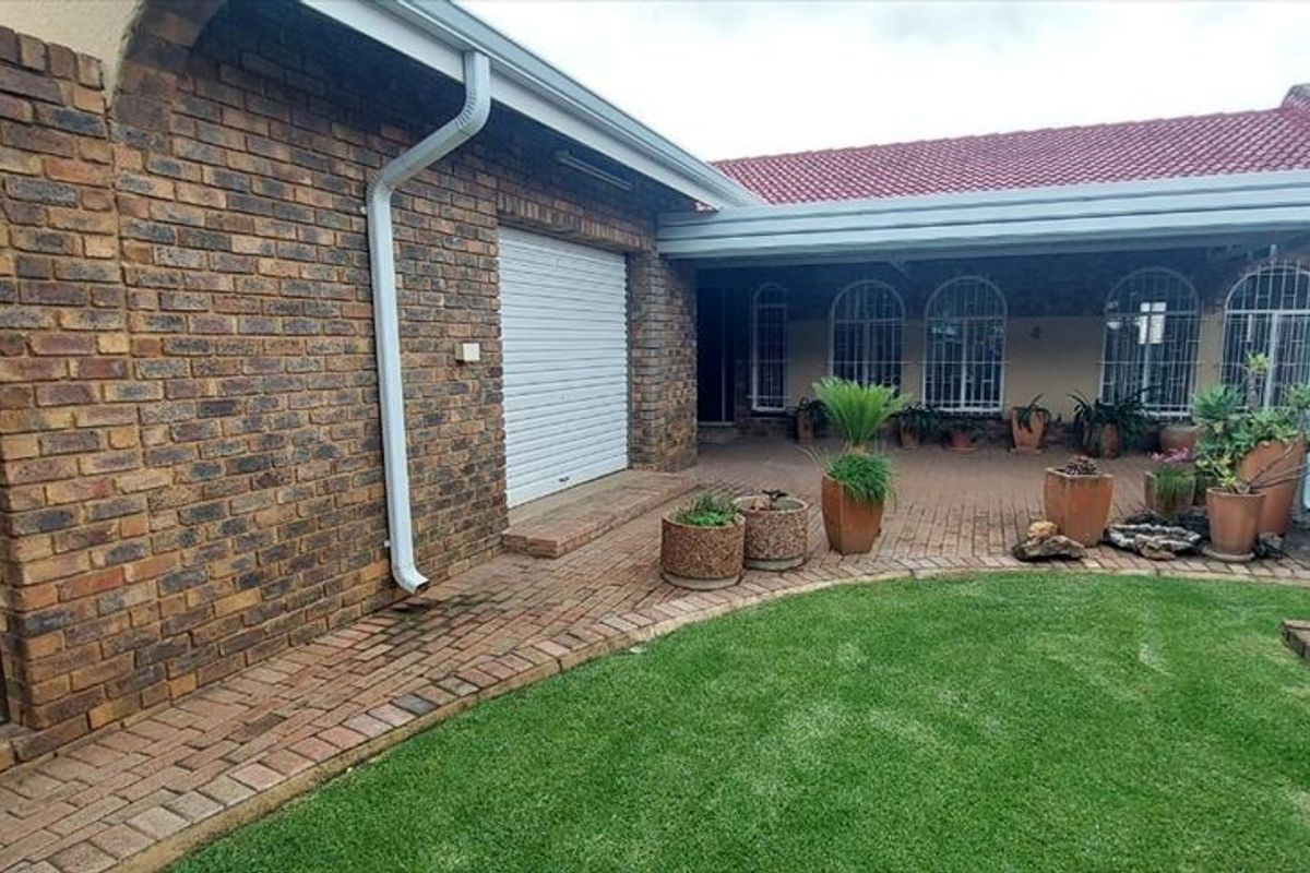 A private rear courtyard featuring a paved patio area, face brick exterior walls, and secure access points, complemented by a small lawn.