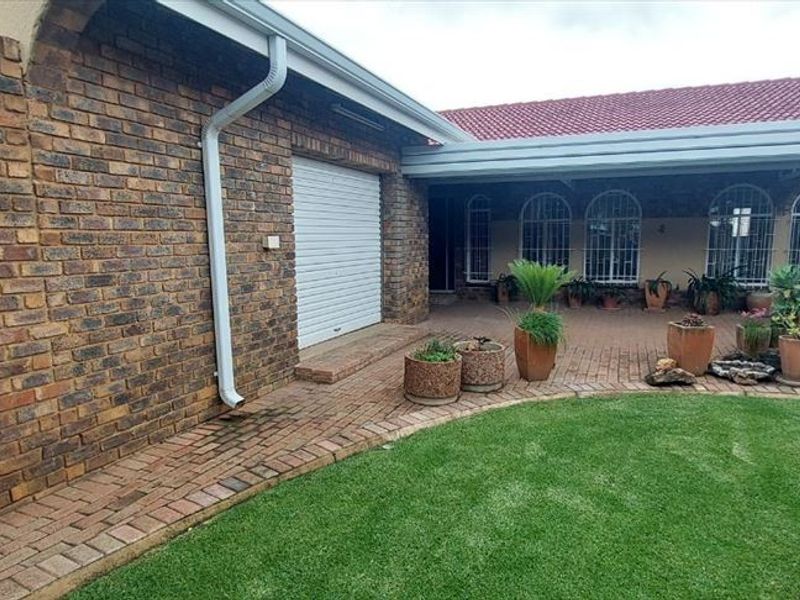 A private rear courtyard featuring a paved patio area, face brick exterior walls, and secure access points, complemented by a small lawn.