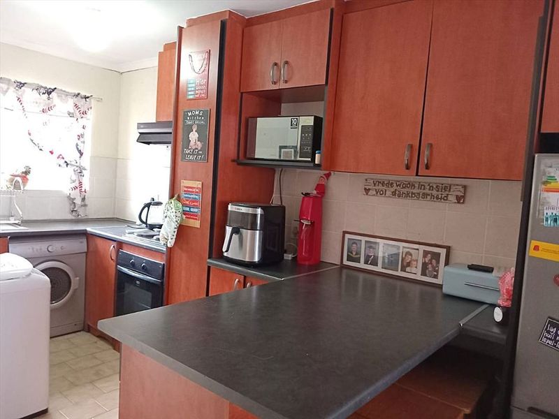 A functional kitchen featuring wood-look cabinetry, dark laminate countertops, a built-in oven, and tiled backsplash, offering a practical layout for daily meal preparation.