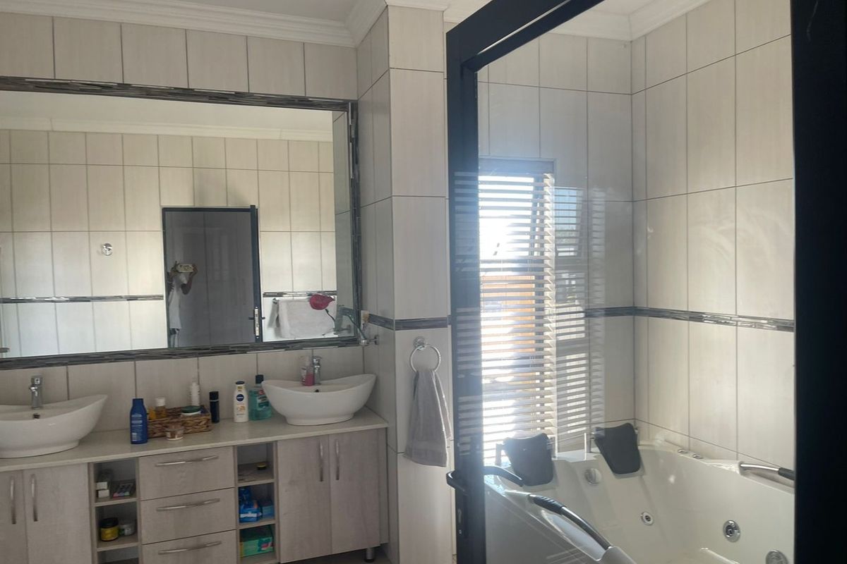 A well-appointed bathroom featuring a double vanity with vessel sinks, a large wall mirror, and a jetted bathtub with tiled surrounds.
