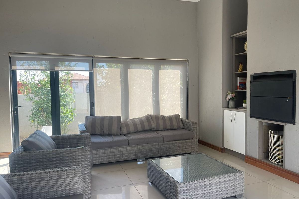 A bright living room featuring large sliding glass doors, tiled flooring, and a built-in fireplace with integrated shelving.