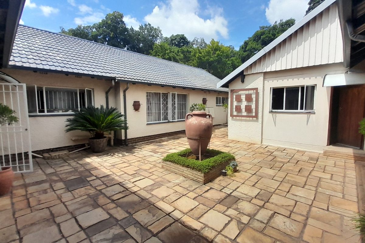 A well-maintained rear courtyard featuring stone paving, a central brick planter, and secure access points to the main dwelling.
