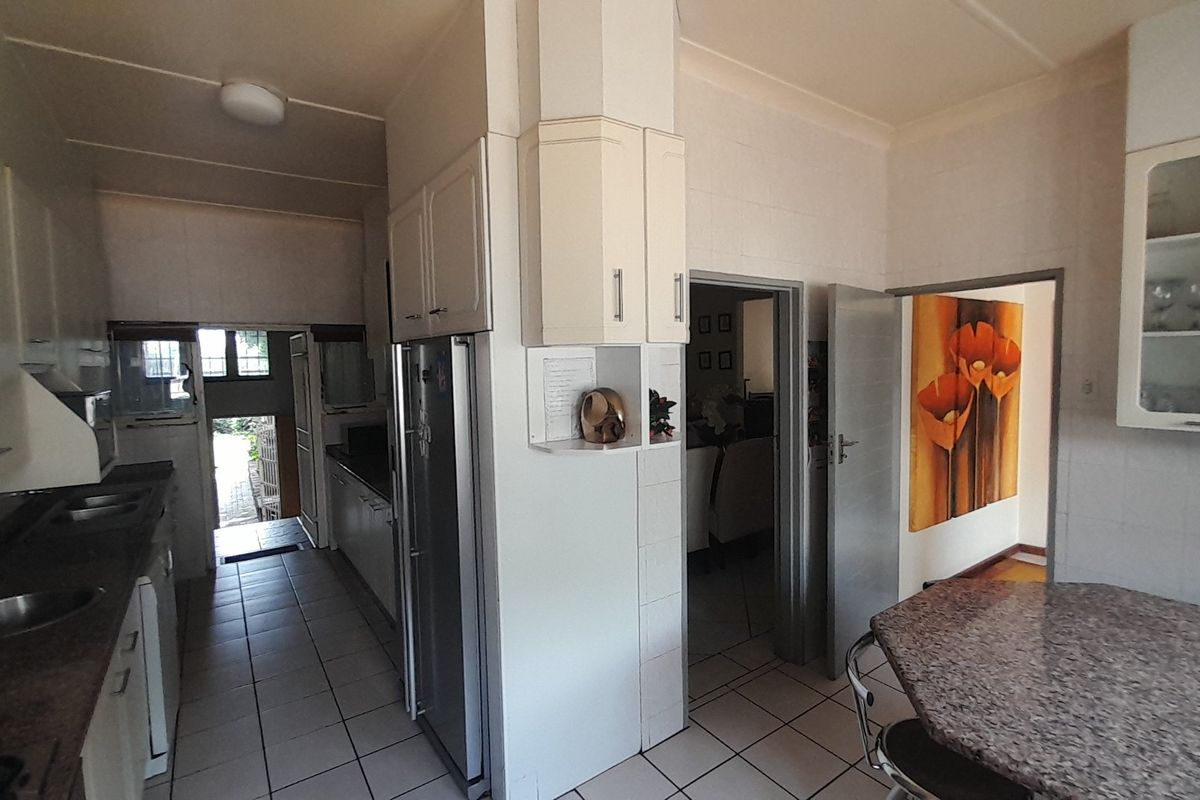 A functional kitchen featuring built-in cabinetry, granite countertops, and tiled flooring, offering a practical layout with direct access to adjacent living areas.