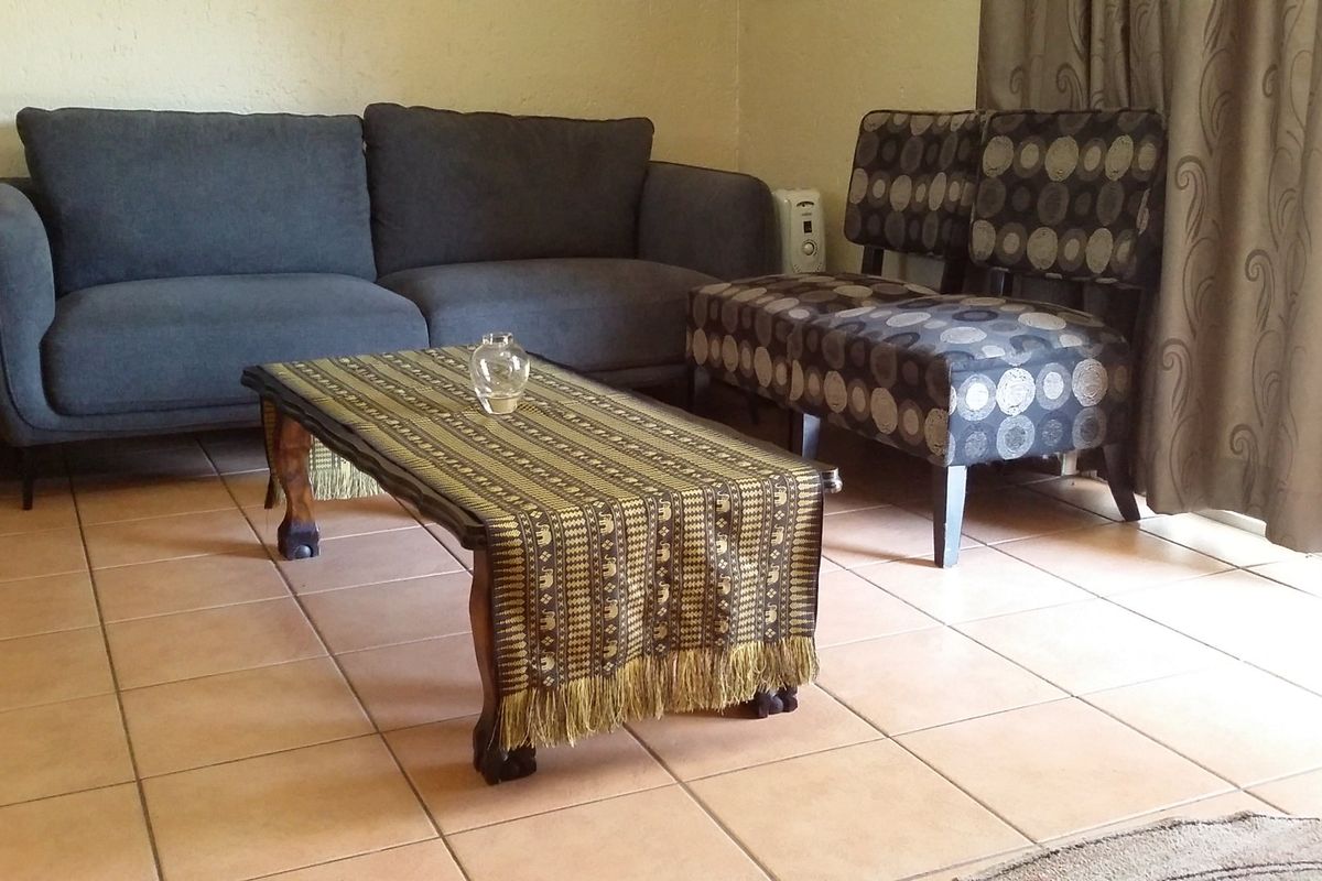 A living room area featuring neutral ceramic tile flooring and access to an outdoor space via a sliding glass door.