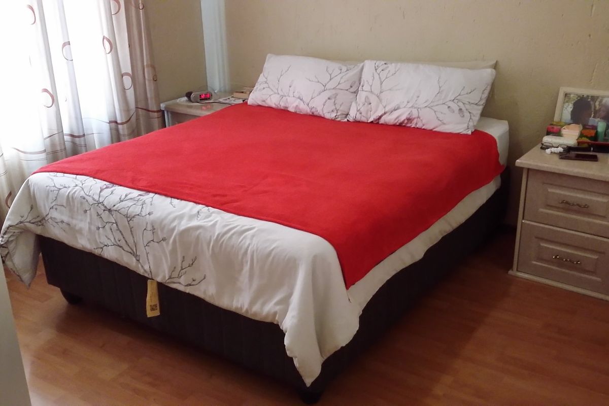 A functional bedroom featuring laminate flooring and a built-in wardrobe, providing a comfortable and practical living space.