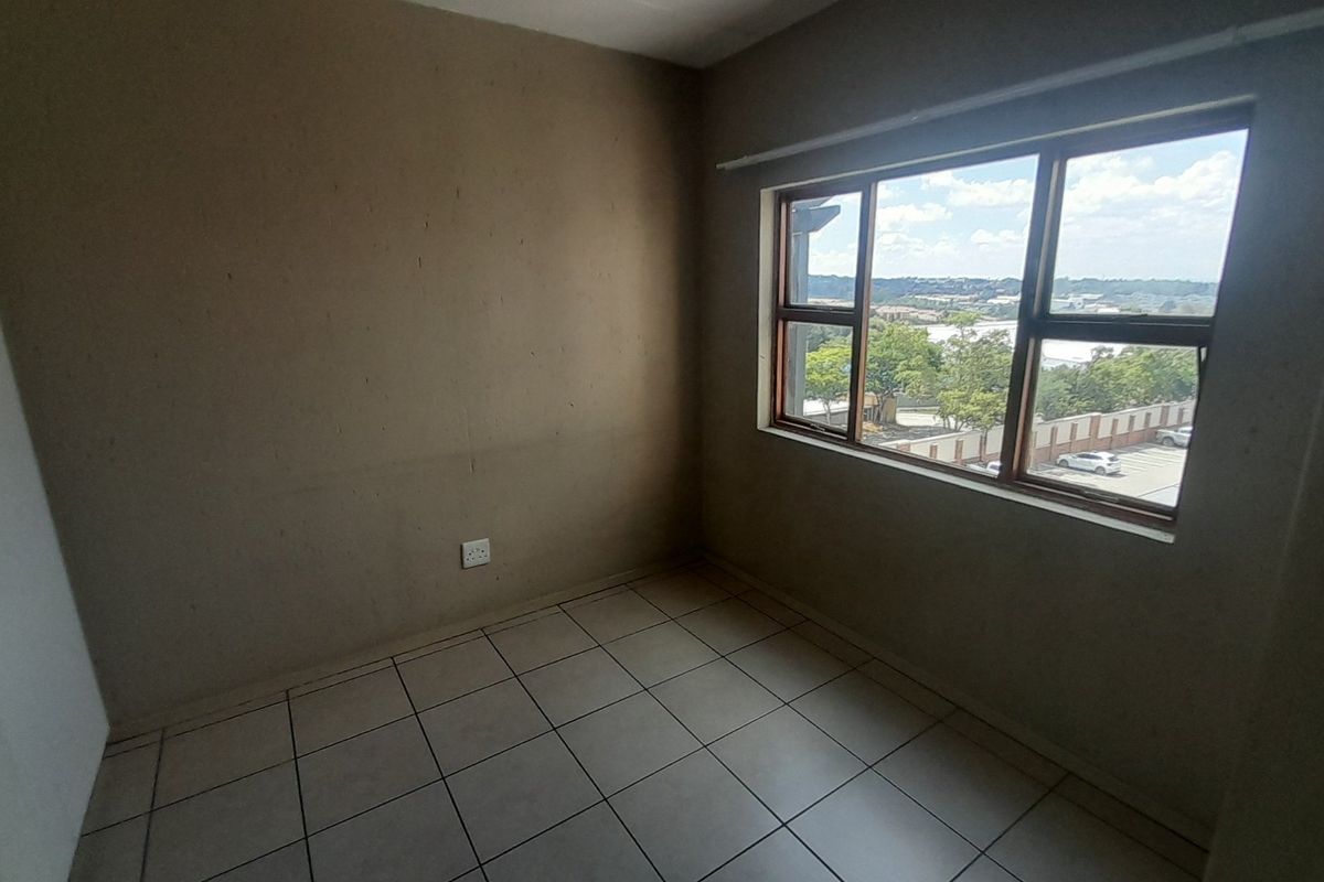 An empty bedroom featuring tiled flooring, a built-in cupboard, and a window with exterior views.
