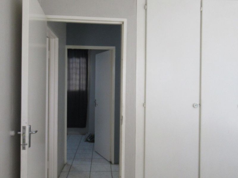 A functional hallway featuring built-in cupboards and tiled flooring, providing access to adjacent rooms within the apartment.